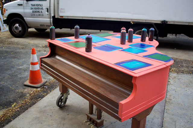 A grand piano being spray painted