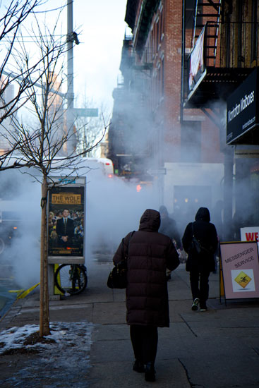 People walking through a large steam cloud