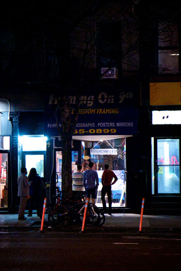 People viewing art for sale in a closed store at night