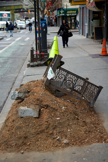 A pile of soil and debris in a destroyed sidewalk planter