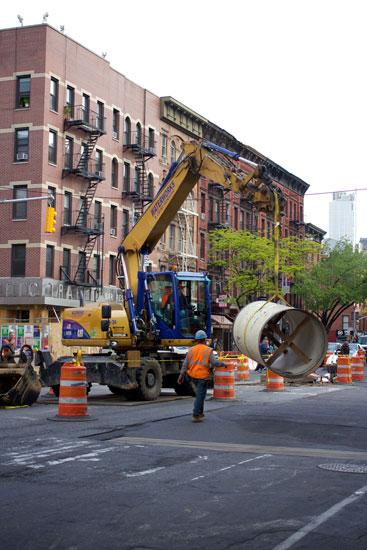 Workers moving a section of pipe in the middle of 9th Ave